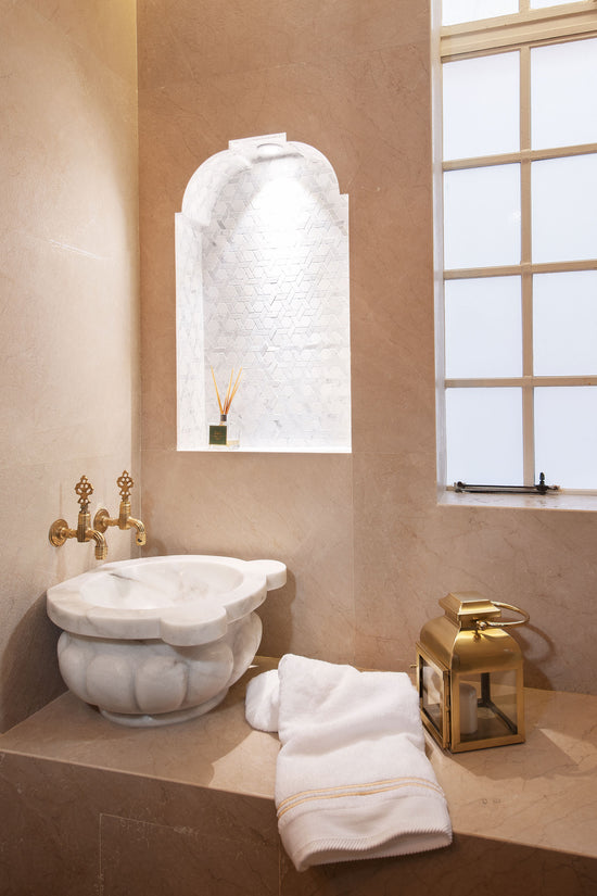 Lavatório clássico em pedra com torneiras douradas, na casa de banho renovada do apartamento de Campo de Ourique.